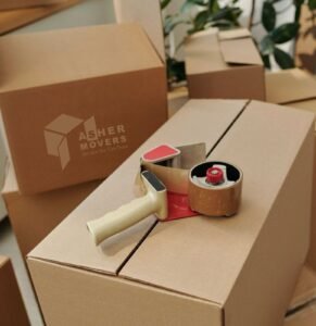 Packing tape dispenser placed on sealed cardboard moving boxes prepared for safe home or office relocation